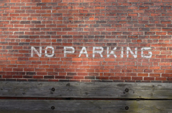 No parking painted on brick wall in white letters 