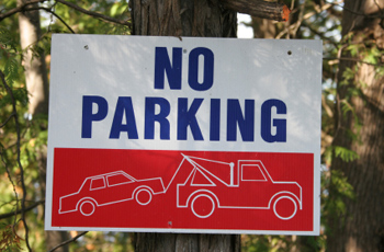 No parking sign on a tree with picture of tow truck 